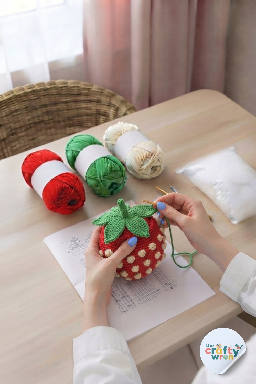 Green crochet leaves are sewn onto the stuffed 3D strawberry bobble crochet stitch cushion top.