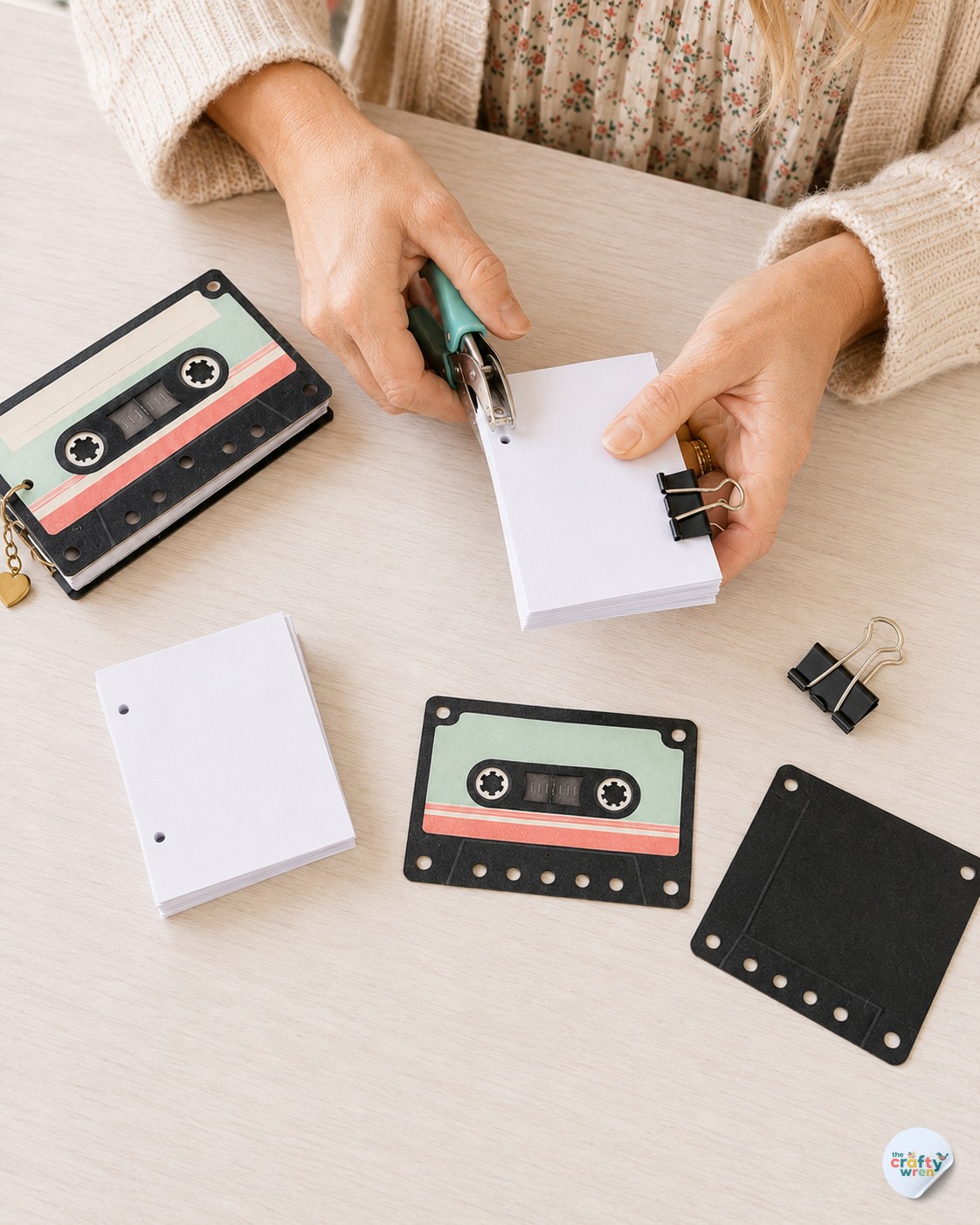 Binder clips holding paper steady while punching holes for a cassette tape flipbook gift