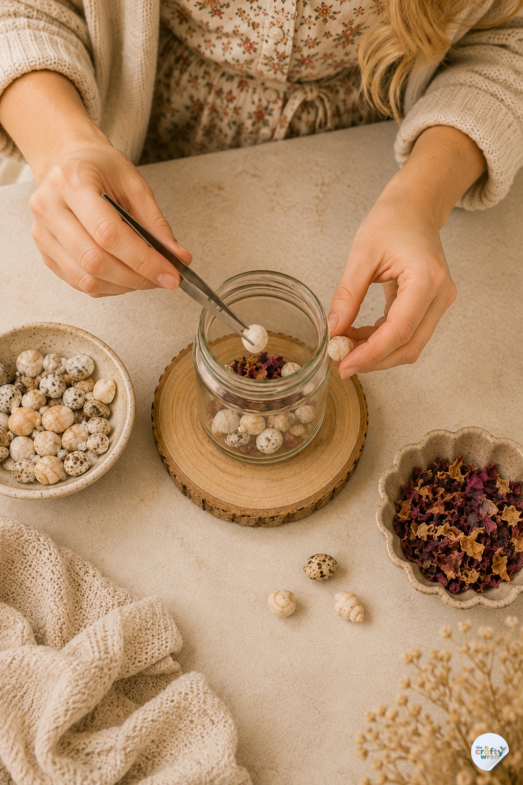 Wren using tweezers to arrange shells inside a jar for a homemade eternal candle