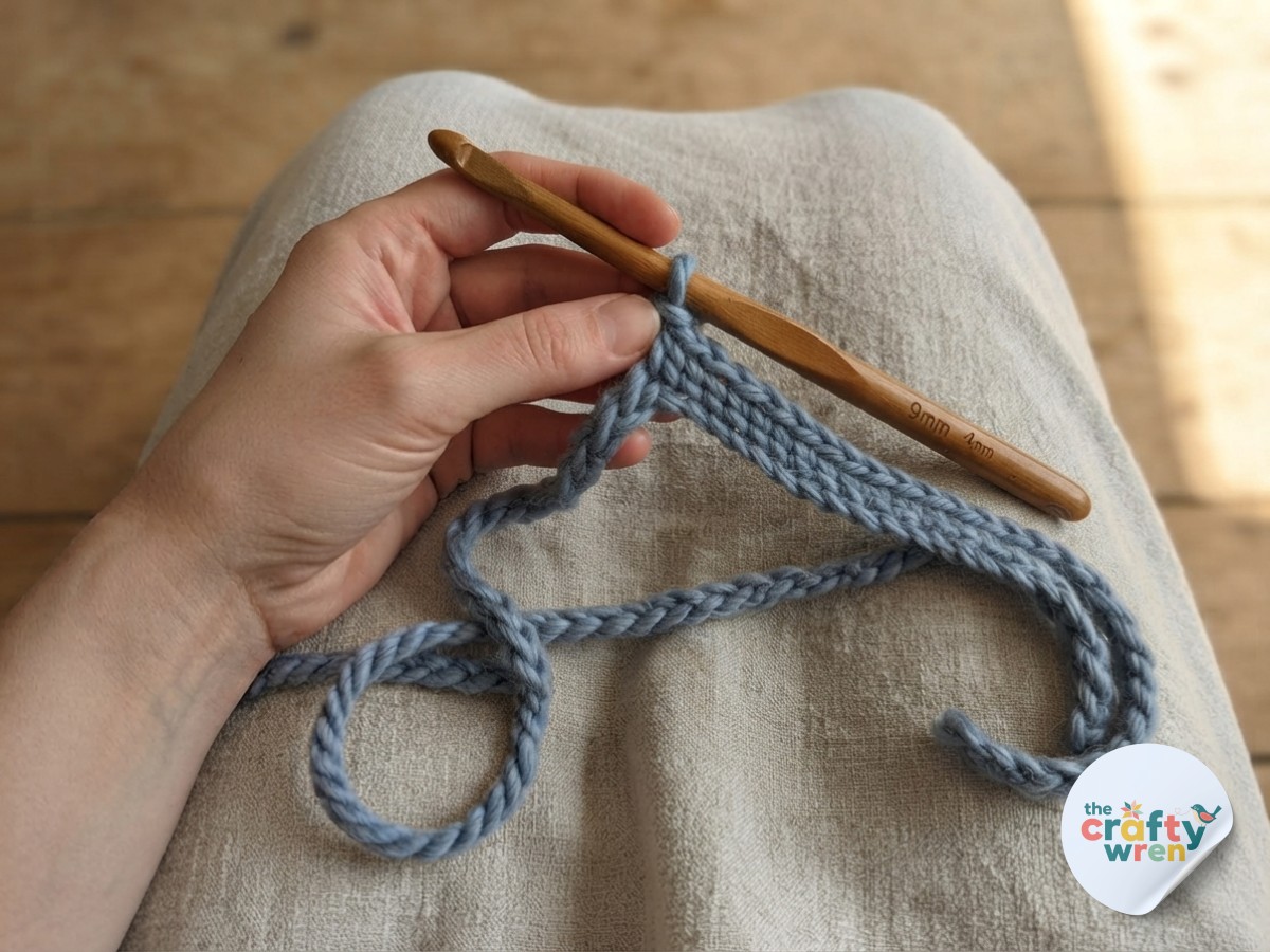 A single crochet base row taking shape, forming the flat strip that anchors this easy textured crochet blanket.