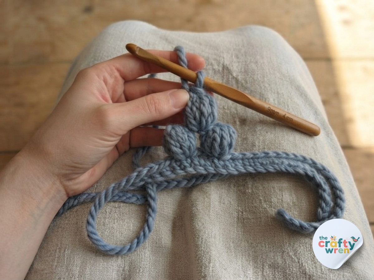 The first puff stitch cluster forming a small bobble, the signature texture of this easy crochet blanket pattern.