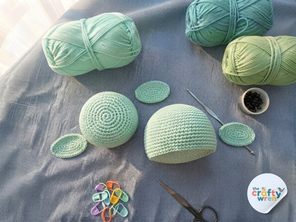 Four flat mint flipper pieces laid beside the body ready to join the crochet sea turtle plushie