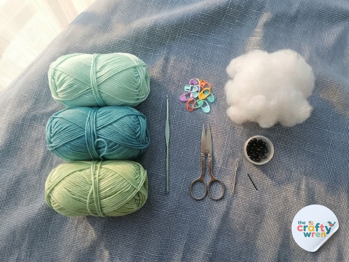 Flat lay of yarn, hook, and stuffing needed to start a no-sew crochet sea turtle plushie project