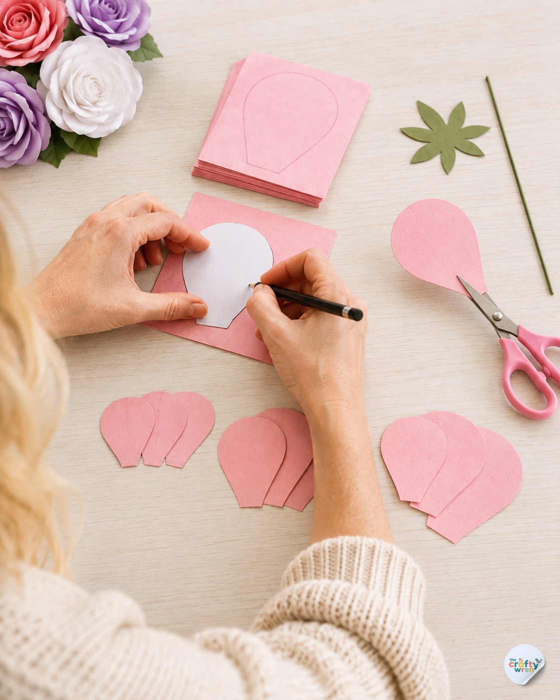 Tracing a rose petal template onto pink cardstock before cutting for a paper rose bouquet DIY