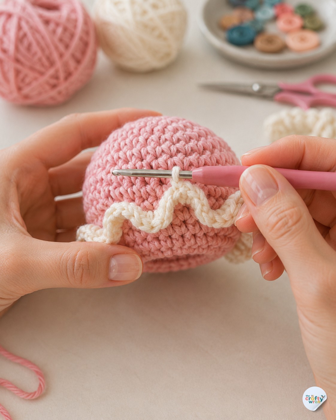 Hands crocheting the cream front loop only ruffle onto a pink jellyfish keychain crochet bell