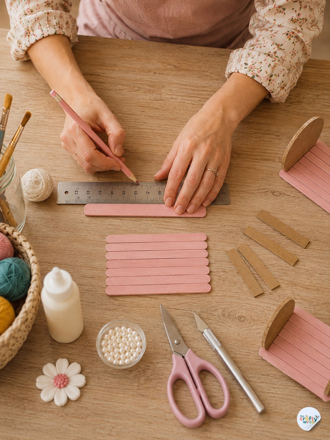 Close-up of hands measuring and marking a craft stick for the popsicle stick treasure box project.