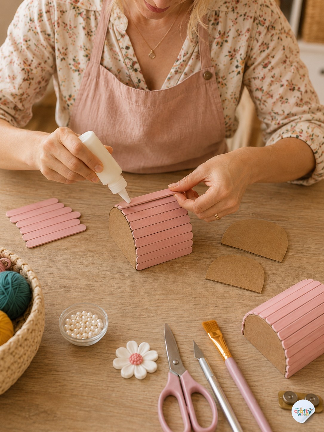 Gluing the curved lid shell onto the popsicle stick treasure box during real-time assembly.